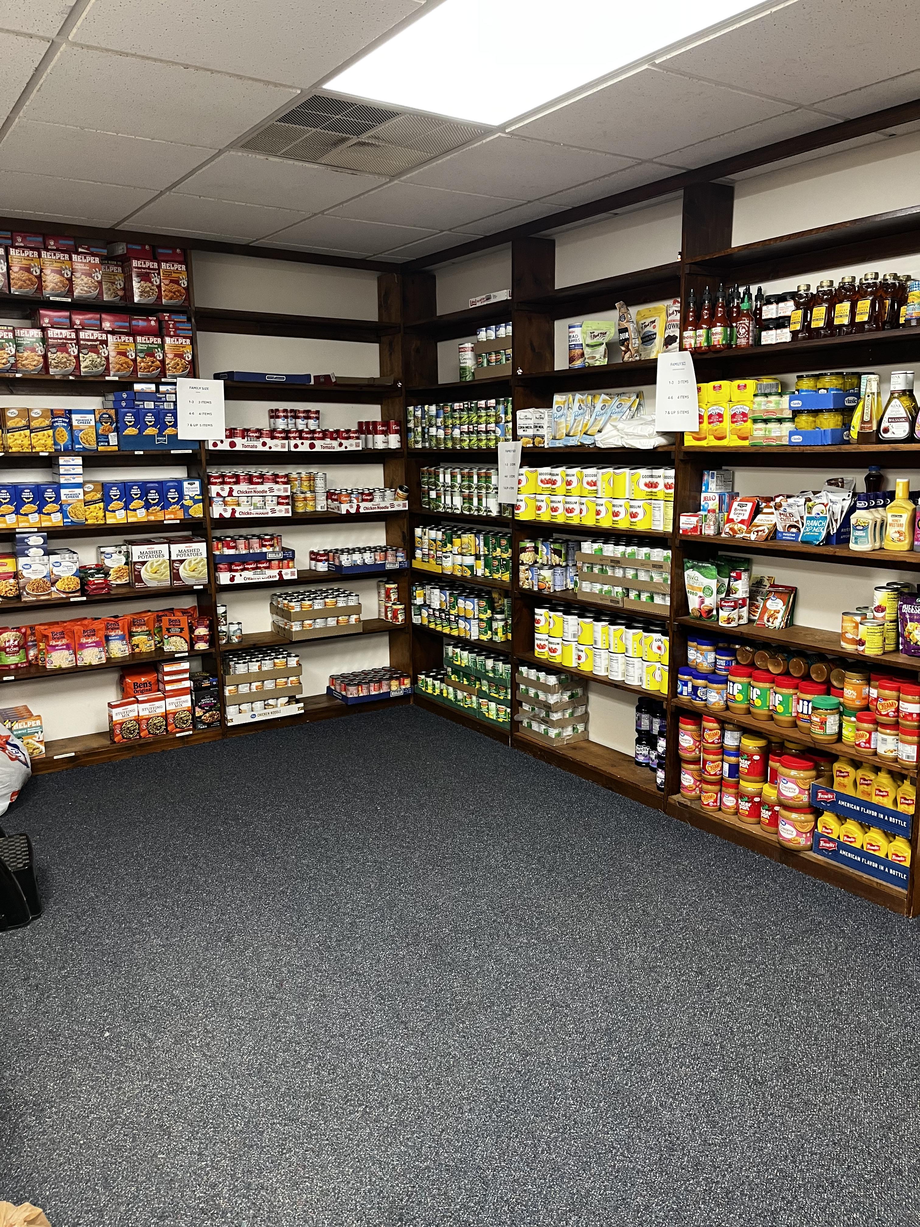 Food pantry shelves stocked with canned goods, pasta, and supplies