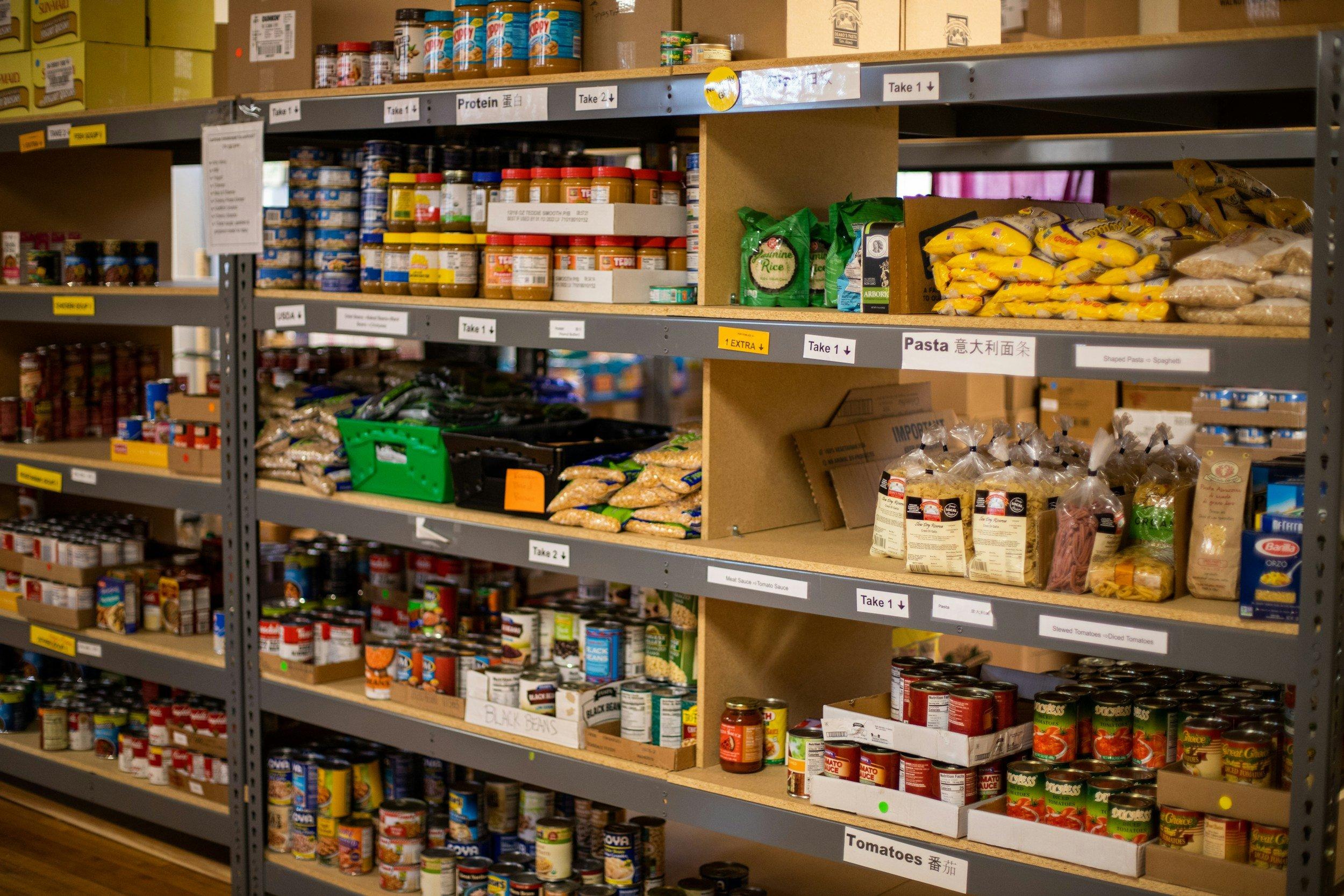 Food pantry shelves stocked with canned goods, pasta, and supplies